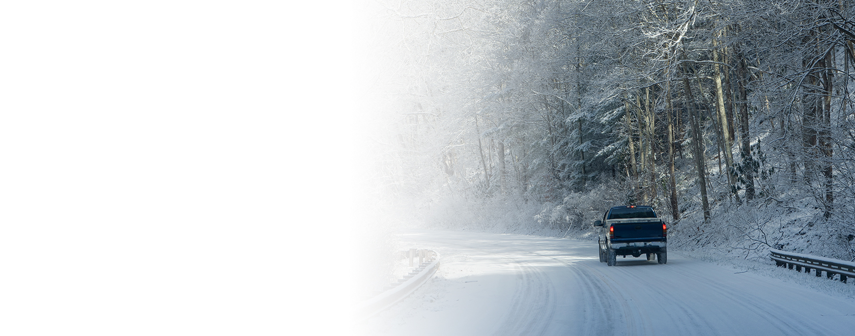 lone black truck travelling remote snow-covered road in winter